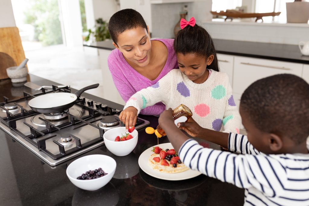 Mother and children preparing food on a worktop in kitchen